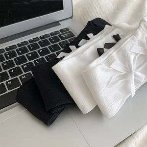 Detail of Lolita style knit calf socks with side satin bows on a metallic surface