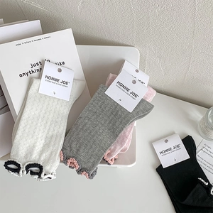 Detail of knitted mesh socks with ruffled edges in white, grey, pink, and black colors