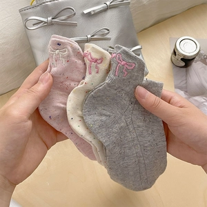 Gros plan sur la broderie nœud et le fil moucheté coloré de ces socquettes en coton doux