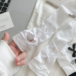Detail view of Lolita style hollow-out calf socks with bowknot decoration on a white bedsheet