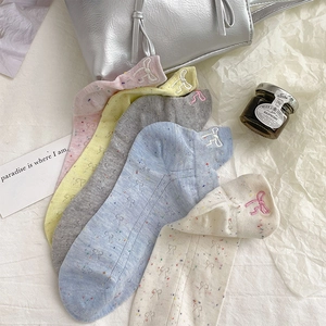 Gros plan de chaussettes en coton avec texture en fil nep et broderies de nœuds délicats