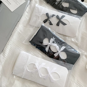 Detail view of Lolita style socks with delicate bows and branded packaging inserts