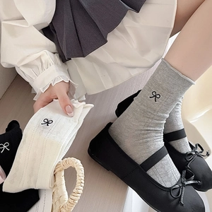 Detailed embroidery of small black bows on gray and white knit calf-high socks