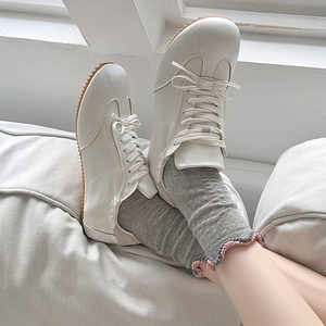 Detail of white mesh socks with pink wavy edges paired with lace-up sneakers