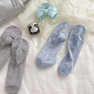 Détail de chaussettes en coton gris et bleu avec texture mouchetée et nœuds brodés