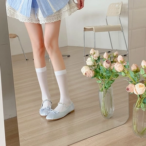 Detail of light blue satin Mary Jane ballet flats with pearl straps and bow accents