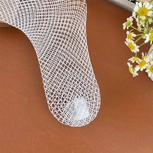 Detail of white diamond mesh fishnet stockings with daisy decoration on brown background