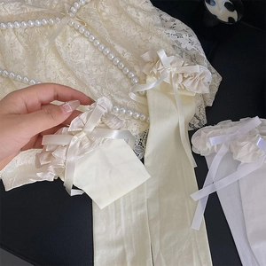 Détail de chaussettes blanches à volants avec nœuds en satin et perles fines