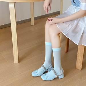 Detail of light blue sheer velvet socks with pearl chain Mary Jane shoes on a model