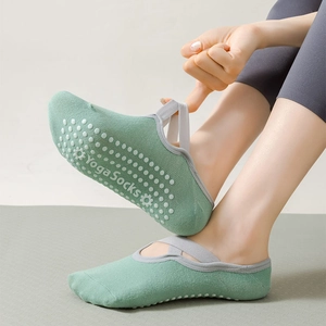 Detail of yoga socks with green knit fabric, gray cross straps, and non-slip silicone soles