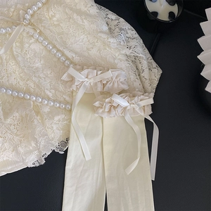 Détail de chaussettes hautes crème avec volants en dentelle et nœuds en satin élégants