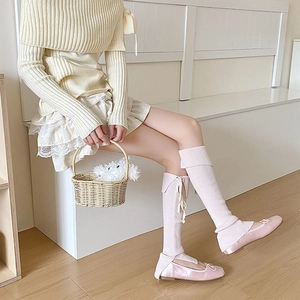 Dettaglio di scaldamuscoli in maglia rosa con fiocchi e pizzo in estetica balletcore