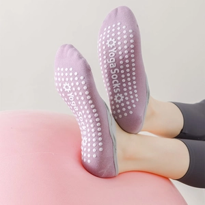 Detail of light purple yoga socks with white anti-slip silicone dots on a yoga ball
