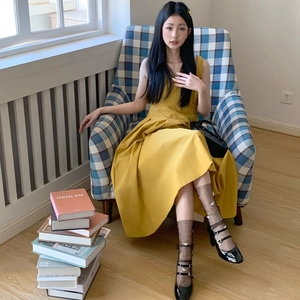Elegant sleeveless ginger yellow midi dress with pleated skirt design on a model