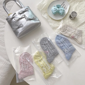Détail de cinq paires de chaussettes à pois pastels en sachets zippés sur table