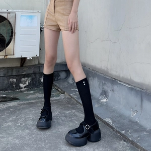 Detail of black platform Mary Janes with heart-accented socks in an outdoor setting