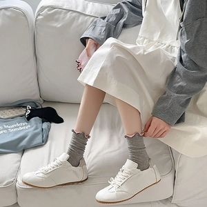 Detail of grey mesh knit socks with pink ruffled edges paired with white sneakers