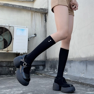 Close-up of black platform Mary Jane shoes with mesh heart patterned knee-high socks