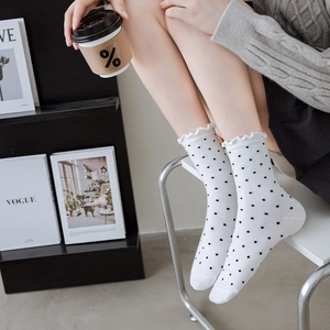 Detail of white cotton mid-calf socks with black polka dots and ruffle lettuce trim