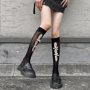 Detail of black hollow-out mesh socks with white satin bows and schoolgirl punk style