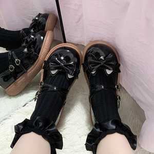Gros plan de chaussures Mary Jane en cuir verni noir avec nœud et chaussettes à dentelle