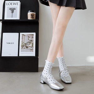 Detail of silver Mary Jane shoes with polka dot ruffle socks in a stylish minimalist setting