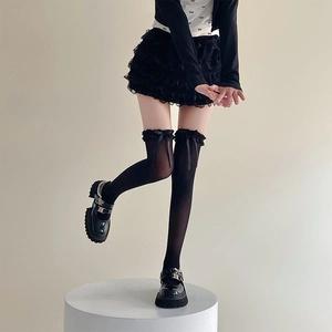 Détail de chaussettes hautes noires avec bordure en dentelle et nœud en ruban