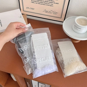 Close-up of three pairs of Lolita style fishnet stockings with lace trim in retail packaging