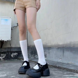 Close-up of black platform Mary Janes with silver buckles and white patterned socks