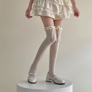Détail de chaussettes hautes blanches avec dentelle délicate et nœuds en ruban