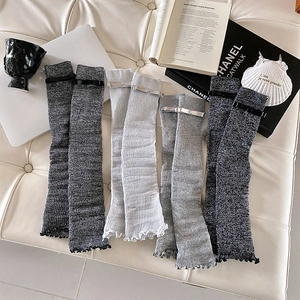 Detailed texture of knit leg warmers with bow accents and ruffled edges in grey tones