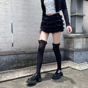 Détail de chaussettes montantes en dentelle noire et chaussures Mary Jane à chaînes