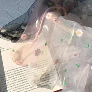 Close-up of delicate daisy embroidery on sheer mesh fabric in black, pink and white