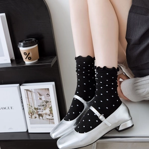 Detailed view of black polka dot mid-calf socks with ruffle trim and silver Mary Janes