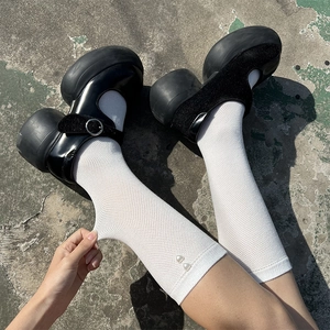 Detail of white mesh lolita socks with heart pearls paired with black Mary Jane shoes
