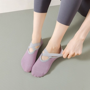 Close-up of purple yoga socks with gray criss-cross straps on a green fitness mat