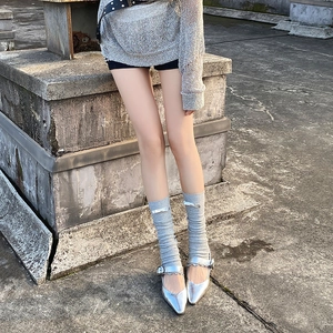 Detail of silver Mary Jane shoes paired with grey knit leg warmers and bow accents