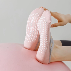 Detail of pink yoga socks with criss-cross straps and anti-slip silicone grippers on sole
