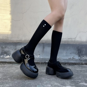 Detail of black platform Mary Janes with glossy finish and heart pearl socks