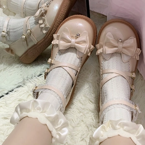 Détail de chaussures Lolita en vernis beige avec nœud et chaussettes à bord en dentelle