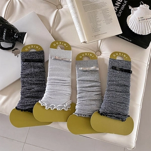 Detail of knitted leg warmers with bow accents and ruffled edges on display cards