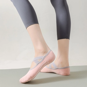Close-up of pink yoga socks with elastic cross straps and silicone non-slip grip dots