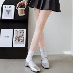 Detail of silver Mary Jane shoes with ruffled white socks in a retro college style
