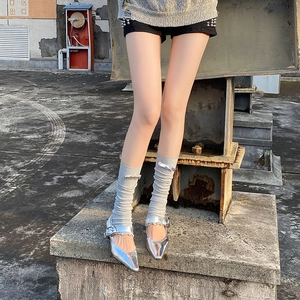Detail of grey knit leg warmers with silver bow paired with metallic Mary Jane shoes