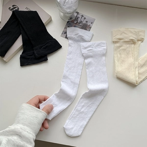 Close-up of hollow lace calf socks with delicate mesh pattern in black white and beige