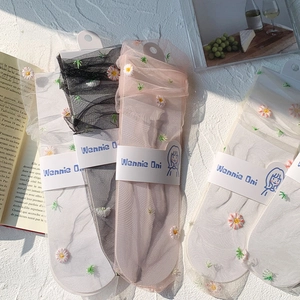 Detailed view of sheer mesh socks with daisy embroidery in multiple colors on a flat surface