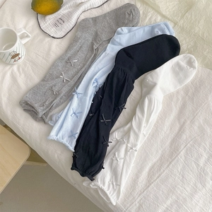 Flat lay of ballet-style mesh knee-high socks with satin bows in four soft colors