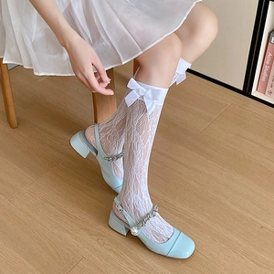 Nahaufnahme weißer Netz-Spitzensocken mit Satinschleife und Perlenriemen Mary Janes