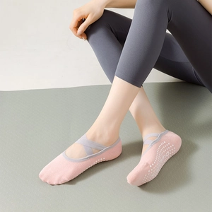 Detail of pink yoga socks with cross straps and white anti-slip silicone dots on soles
