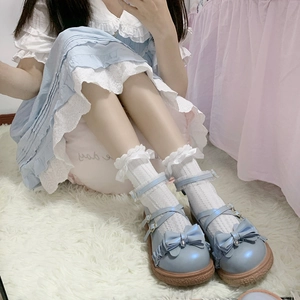 Gros plan sur des chaussures Lolita bleues avec nœuds et chaussettes en dentelle